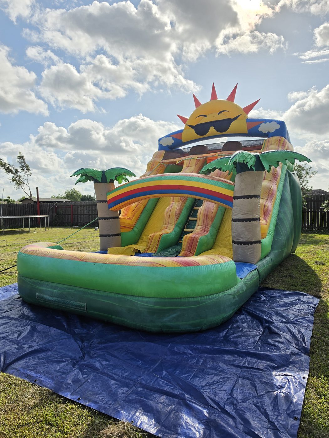 Green Sunshine — tropical water slide with sun mascot and palm trees